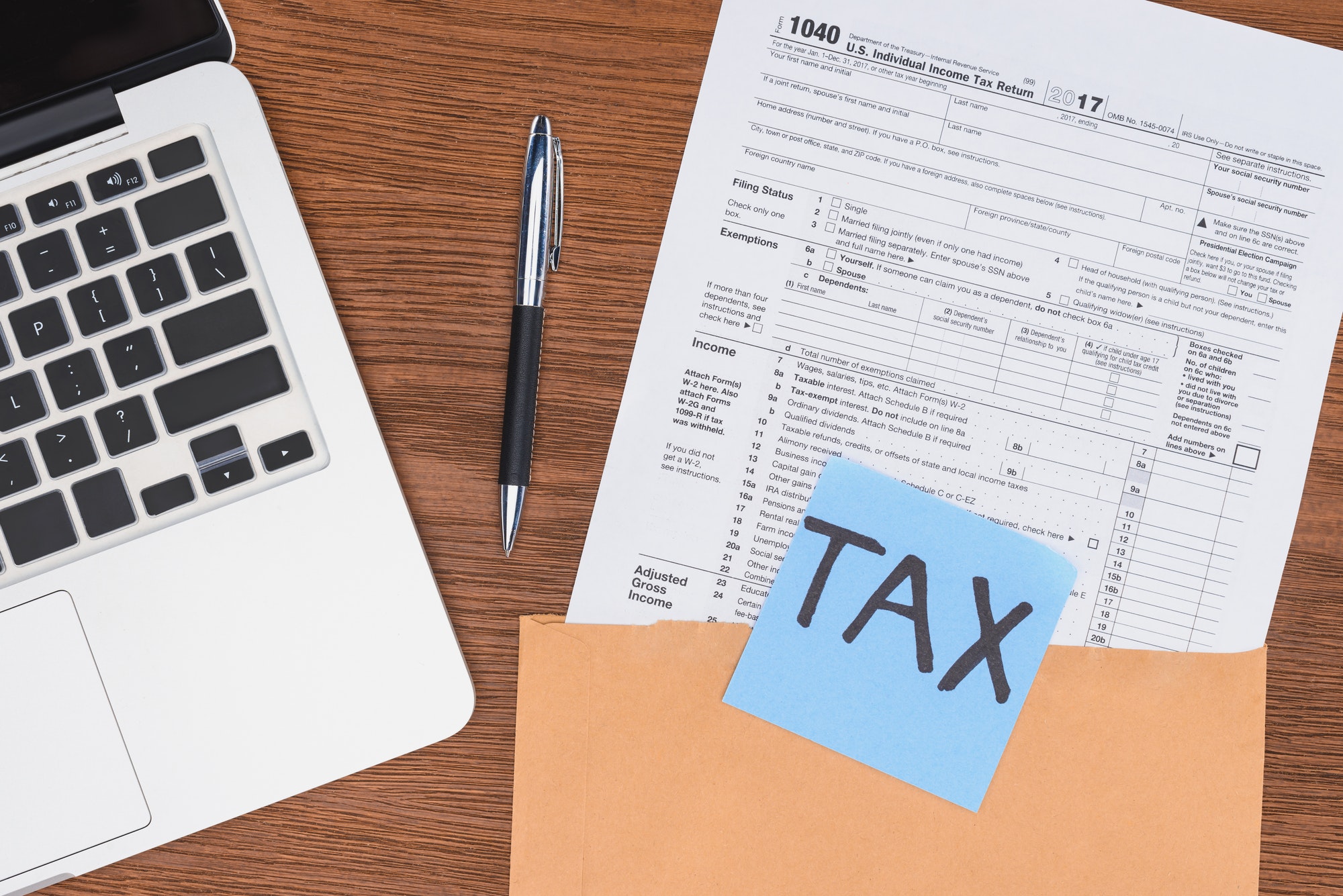 top view of tax form, laptop and blue card with 'tax' word at workplace